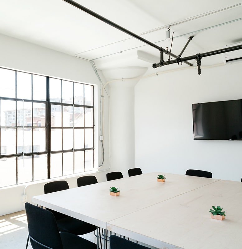 Clean white conference room with black chairs and a tv.