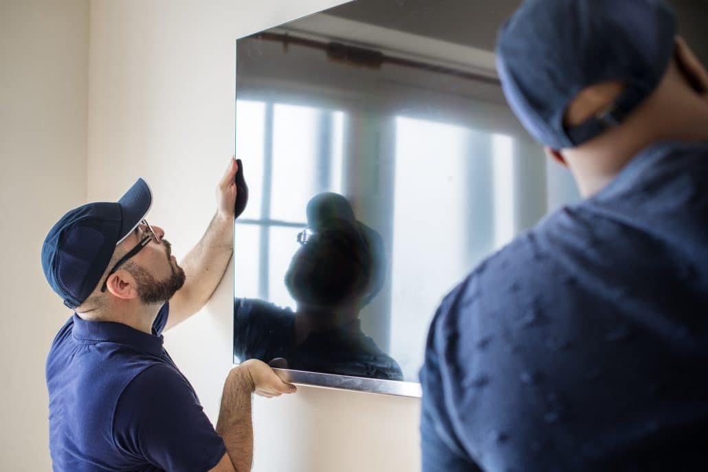 Furniture delivery service concept Two men installing a tv to a wall.