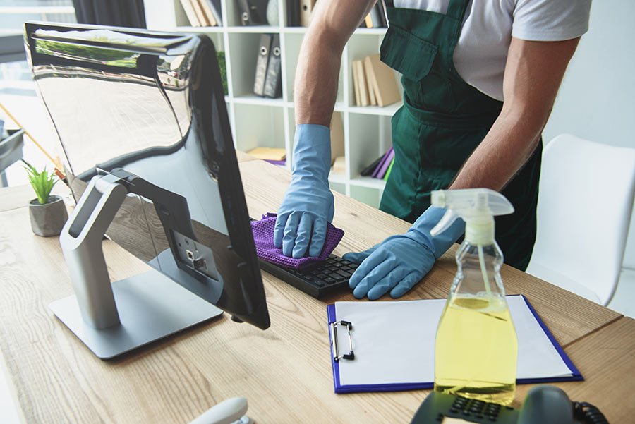Man cleaning a computer keyboard on a desk.