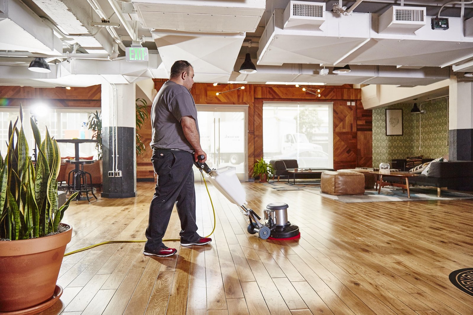 Man cleaning a hardwood floor with a machine.