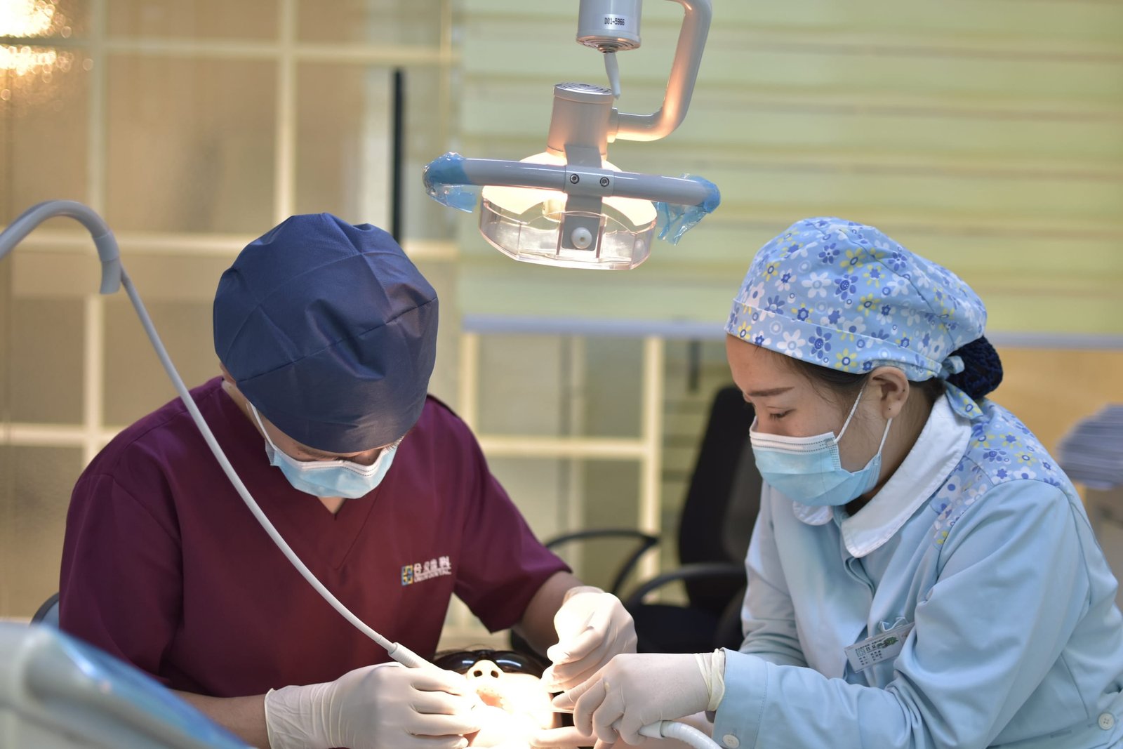 Two dentists cleaning a patient's teeth.