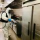Man in protective suit cleaning and disinfecting a kitchen.