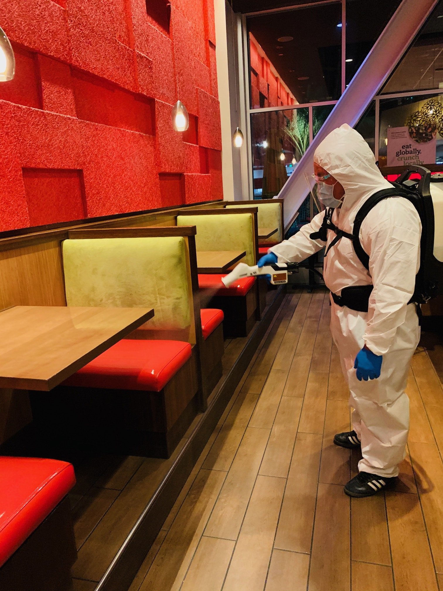 image3 Man in protective suit cleaning and disinfecting booth.