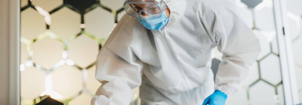 Man in protective suit cleaning and disinfecting table.