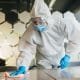 Man in protective suit cleaning and disinfecting table.