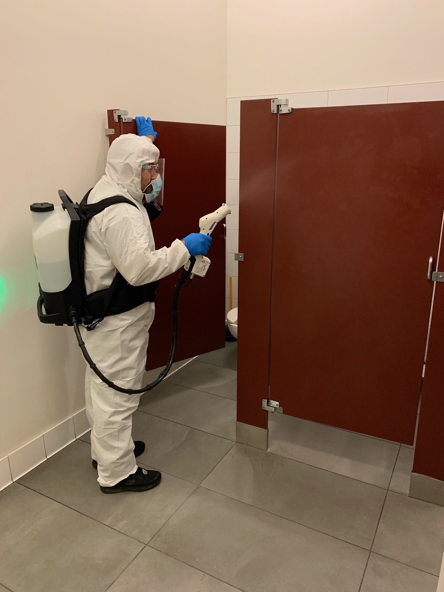 Commercial Disinfecting Services A professional disinfecting the bathroom stall